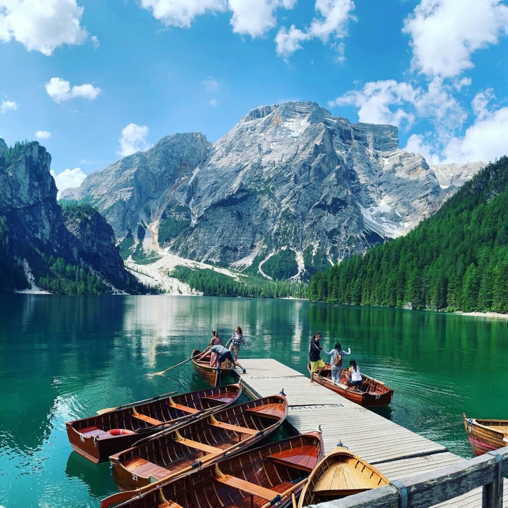 Exploring the serene Lake Braies with wooden boats against the backdrop of towering mountains in Italy.